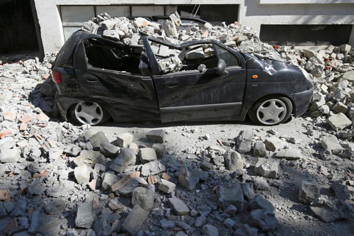 Chiế xe hơi bị bẹp rúm do các tòa nhà đổ sập do động đất ở Amatrice, miền trung Italy. Ảnh: Reuters.