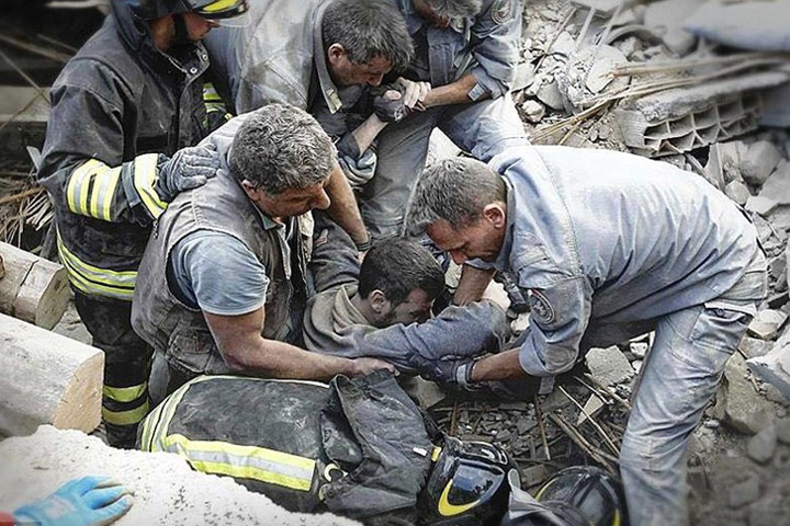 Một đội cứu hộ đang khẽ nâng một người đàn ông ra khỏi một tòa nhà bị sập ở Amatrice. Ảnh: Twitter.
