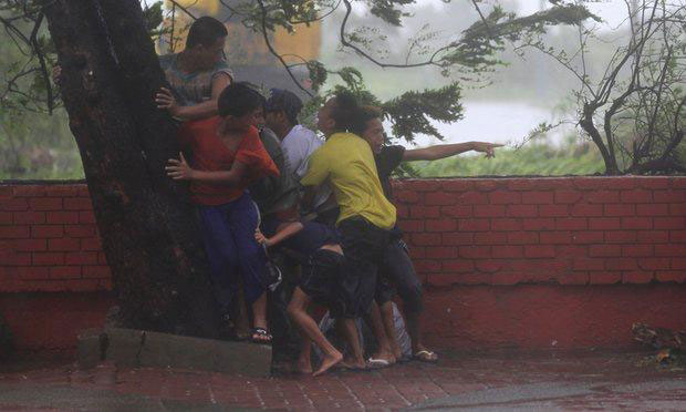 Nhóm thanh niên hoảng sợ bám chặt vào gốc cây, tránh bị cuốn theo chiều gió trong cơn bão Rammasun hoành hành tại Philippines tháng 7-2014.