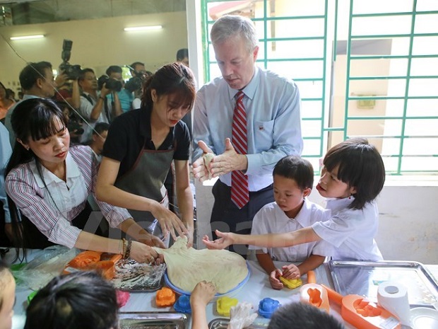 US Ambassador to Vietnam Ted Osius and children at the Vietnam Friendship Village are making full-moon cakes (Source: VNA)