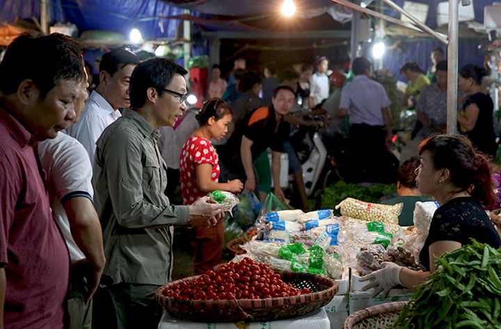 Phó Thủ tướng Vũ Đức Đam hỏi chuyện một tiểu thương buôn bán rau quả tại chợ Long Biên.