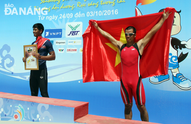 A Thai prize-winner holding a picture of his idol stepping up to the podium instead of carrying his national flag