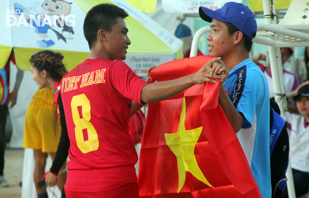 Vietnamese shuttlecock gold winner Dinh Van Duc receiving his national flag before stepping up to the podium to get his medal in the men's single event