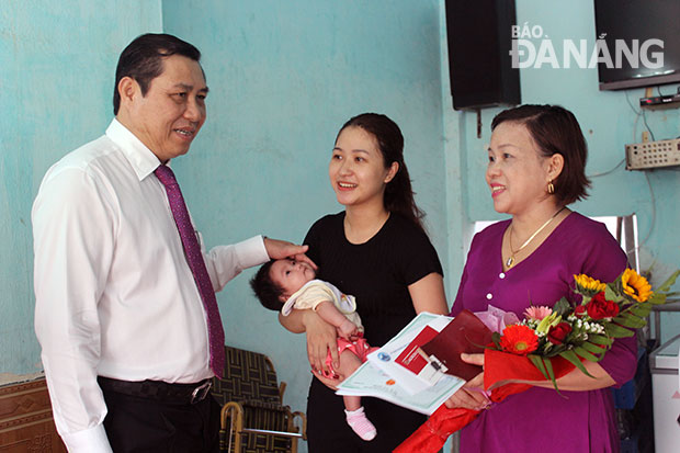 Chairman Tho (left) presenting newborn baby’s documents to the family of Mr Phuong Kha Di from Cam Le District’s Hoa Tho Tay Ward