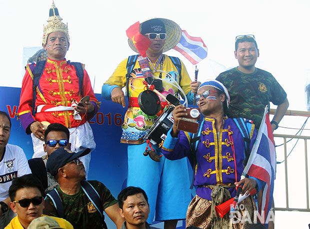 Mr Khamthong (conical hat) beating a drum at a competition    