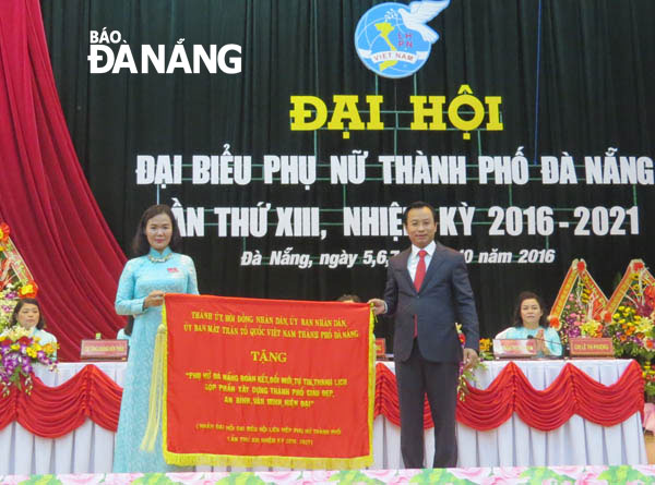 Thay mặt Thành ủy, HĐND, Ủy ban MTTQ Việt Nam thành phố Đà Nẵng, Bí thư Thành ủy Nguyễn Xuân Anh trao tặng Hội LHPN thành phố bức trướng với nội dung “Phụ nữ Đà Nẵng đoàn kết, đổi mới, tự tin, thanh lịch, góp phần xây dựng thành phố giàu đẹp”. Ảnh: NGỌC HÀ