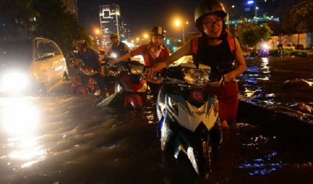 People walk their vehicles through floodwater on a street in Ho Chi Minh City. Tuoi Tre