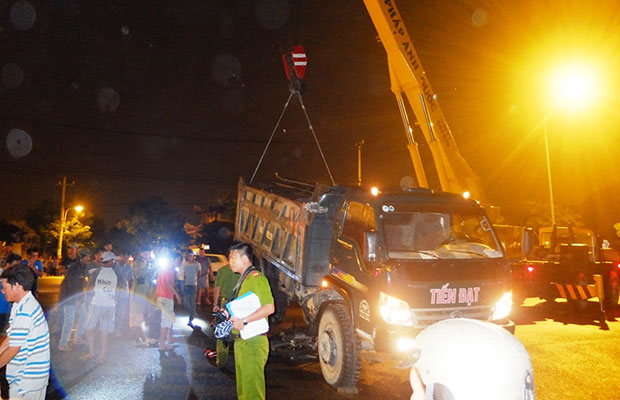 Lực lượng chức năng cho tiến hành cẩu xe ben để đưa xe gắn máy và thi thể 2 nạn nhân bị kẹt dưới gầm xe ra ngoài.