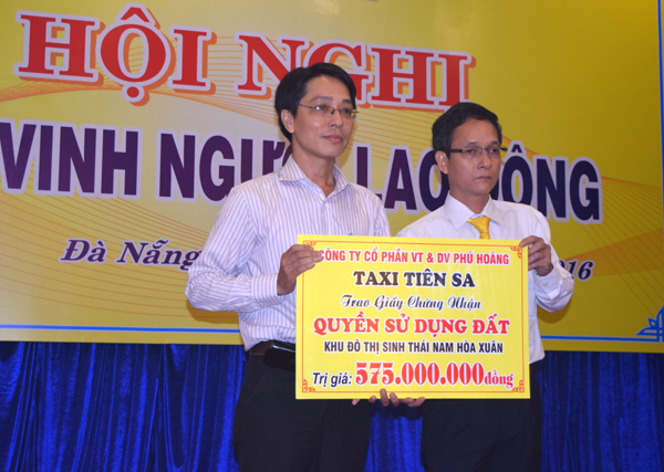 Ông Nguyễn Văn Hiền, Phó Tổng giám đốc Công ty CP Vận tải và dịch vụ Phú Hoàng - Taxi Tiên Sa, trao tặng biểu trưng sử dụng lô đất ở cho thân nhân lái xe bị cướp sát hại. Ảnh: TRIỆU TÙNG