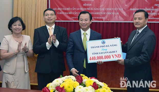 Secretary Anh (second right) giving 440 million VND from the city budget to Savannakhet Province to implement some local social welfare activities 