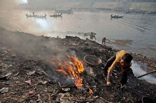 Cậu bé Bangledesh đang đốt đống kim loại phế liệu bên dòng sông Buriganga ở Dhaka. Cách tái chế vật liệu như thế này không chỉ nguy hiểm cho sức khỏe của cậu bé mà còn làm ô nhiễm dòng sông ở ngay sát sau lưng cậu bé. 