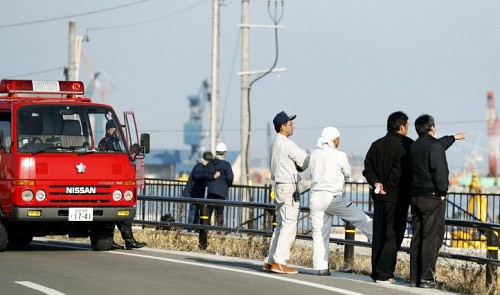 Firefighters and local residents look toward the port to check the water level after tsunami advisories were issued following an earthquake in Soma, Fukushima prefecture, Japan, in this photo taken by Kyodo November 22, 2016.