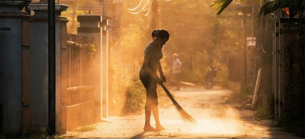 As dawn breaks on the horizon, Réhahn captures a woman sweeping the street with a broom. 