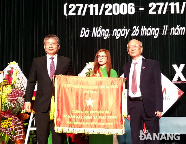 Phó Chủ tịch UBND thành phố Nguyễn Ngọc Tuấn (trái) trao Cờ ghi nhận thành tích 10 năm của UBND thành phố cho lãnh đạo Trường Đại học Kiến trúc Đà Nẵng  