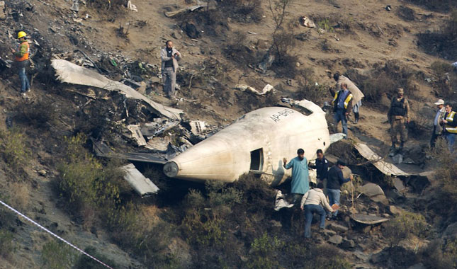 Các nhà điều tra Pakistan xem xét chiếc máy bay rơi.   Ảnh: AP