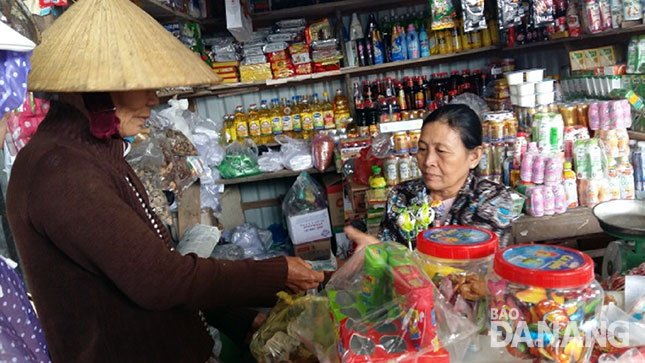 Bà Suyên (trái) mua chai mắm nêm nhỏ ở quầy tạp hóa cô Quyết, để dành ăn cả tuần.