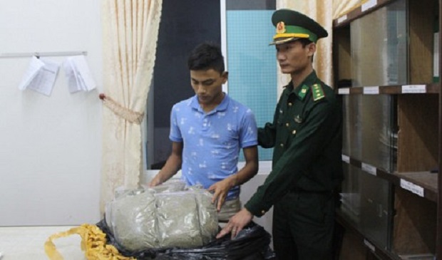 Tran Quoc Rym (L), 24, is seen standing next to his drugs seized by border soldiers in Da Nang City, located in central Vietnam. Tuoi Tre