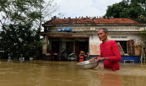 A man wades through floodwaters in front of his home in the central Vietnamese province of Binh Dinh on December 18, 2016. AFP