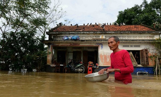 This picture taken on December 18, 2016 shows a man wading through floodwaters in front of his home in the central province of Binh Dinh. Days of unseasonably torrential rains have killed at least 26 people in central Vietnam, authorities said on December 19, inundating swathes of the region including the tourist draw town of Hoi An. Photo by STR/AFP 