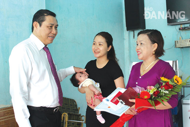 Municipal People’s Committee Chairman Huynh Duc Tho (left) presenting a newborn baby’s documents to the family of Mr Phuong Kha Di from Cam Le District’s Hoa Tho Tay Ward