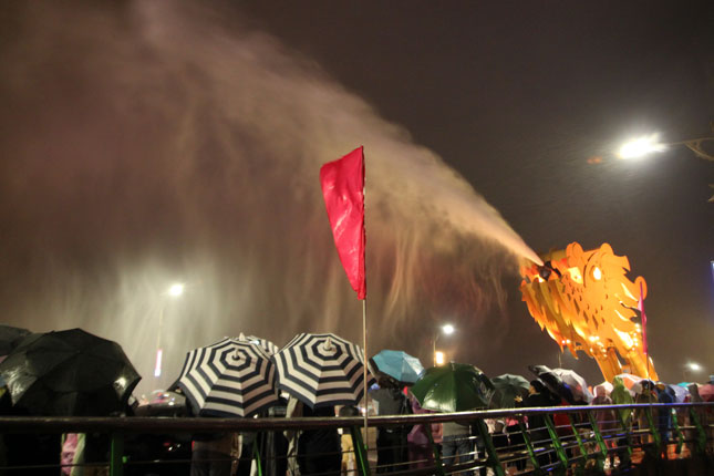 Local residents and visitors watching the dragon's head breathing fire and squirting water at the eastern end of the Rong (Dragon) Bridge