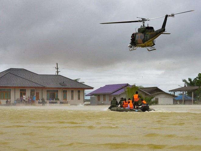 A rescue boat and a helicopter moving towards a group of stranded people in the Srinakarin district of the southern Thai province of Phattalung (Photo: Getty)