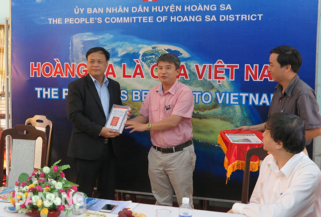  The Deputy Head of the local Institute for Socio-Economic Development, Dr Tran Duc Anh Son (right), presenting a document book about the archipelago to a representative from the islands district’s PC