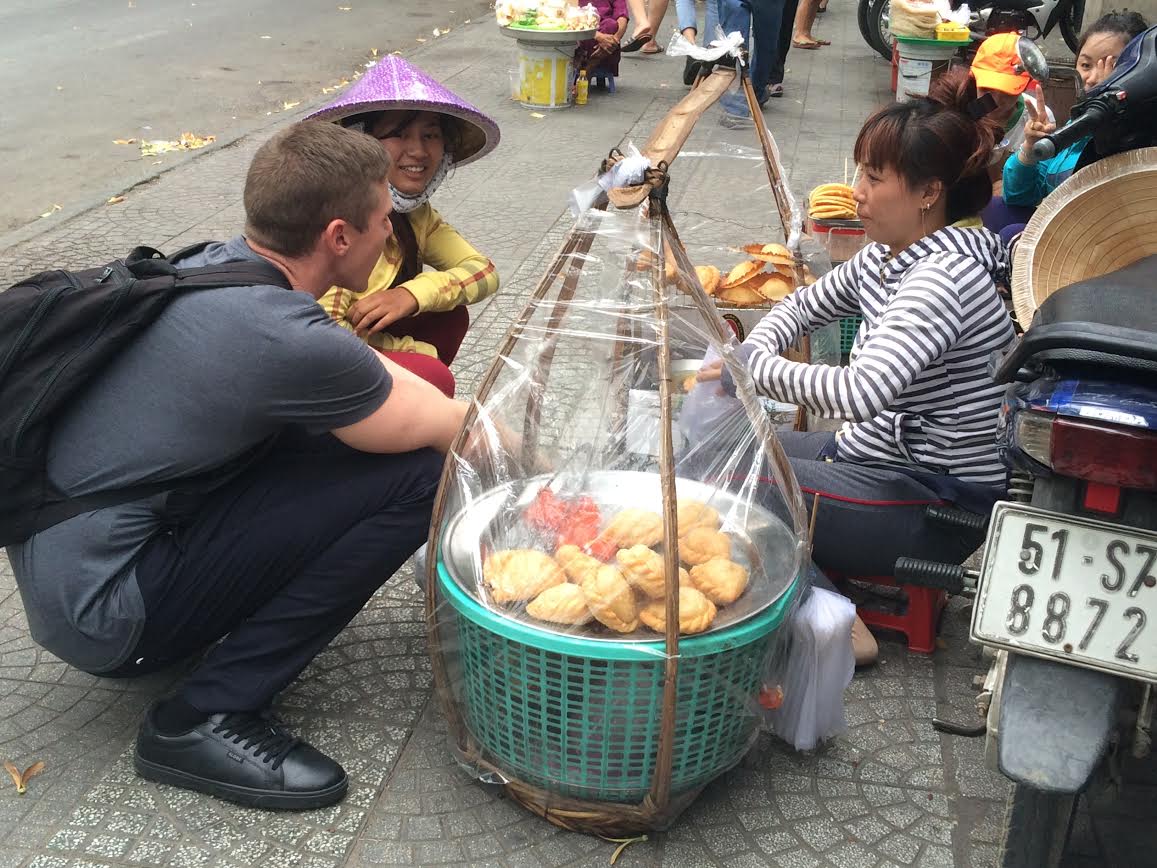 In this photo provided by Andrew Davey, he is seen friendly talking to a street vendor in Vietnam.