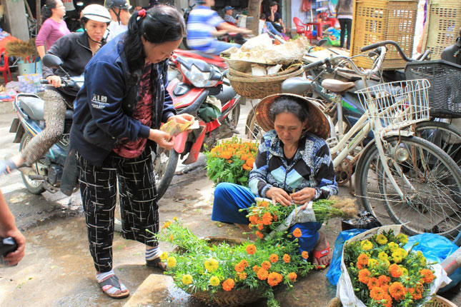 Bà Hồ Thị Thanh (quận Sơn Trà) đến chợ Phước Mỹ mua hoa chuẩn bị cho mâm cúng đêm Giao thừa. “Hôm nay nắng đi mua cho khỏe, lỡ mai mưa lại thì cực lắm,” bà Thanh nói.