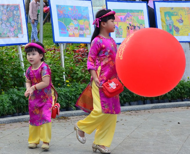 Những em nhỏ mặc áo đẹp vui đùa bên người thân cùng hưởng không khí vui tươi của mùa xuân. Girls in ‘ao dai’ (traditional Vietnamese long dress)