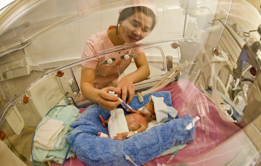 A nurse checks a baby’s body temperature.