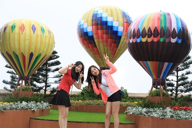 Two young ladies taking a photo with eye-catching hot air balloons at the resort’s Happy Garden