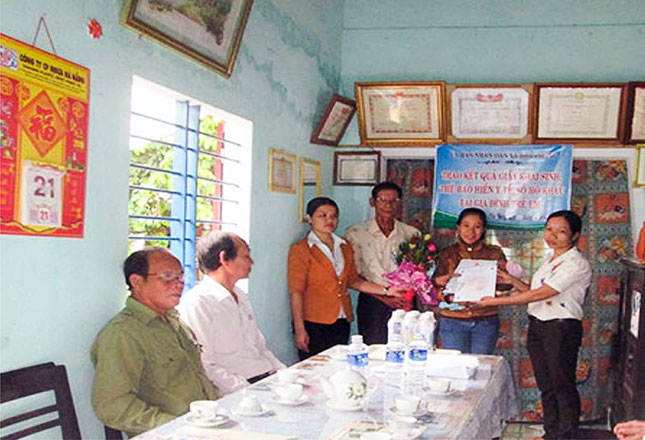 Chị Nguyễn Thị Vân, Chủ tịch UBND xã Hòa Phong (bìa phải) đến tận nhà tặng hoa chúc mừng và trao giấy khai sinh, thẻ BHYT, hộ khẩu cho trẻ sơ sinh.                                                 (Ảnh do nhân vật cung cấp)