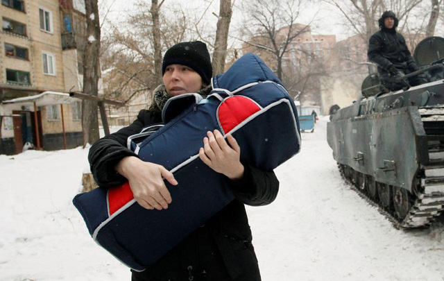 Một phụ nữ bế một em bé đi sơ tán tại Donetsk, Ukraine. (Ảnh: Reuters)