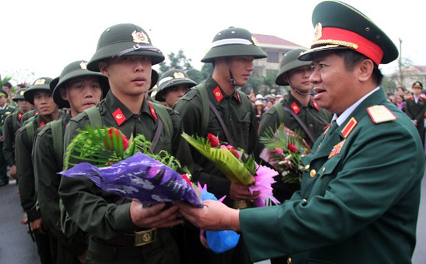  Major General Ngo Quy Duc presenting flowers to some new recruits in the district