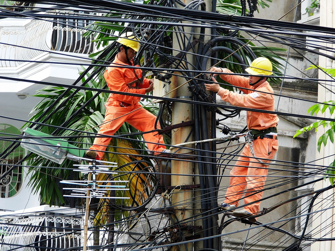 Two workers on an electricity pole in Ha Noi. Photo by Vietnam News Agency