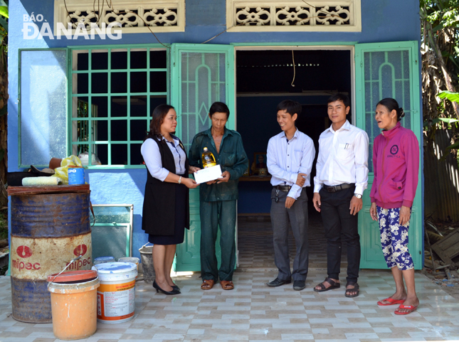 Anh Nguyễn Văn Thạnh (thứ hai, từ trái sang) nhận quà trong căn nhà mới được sửa chữa.