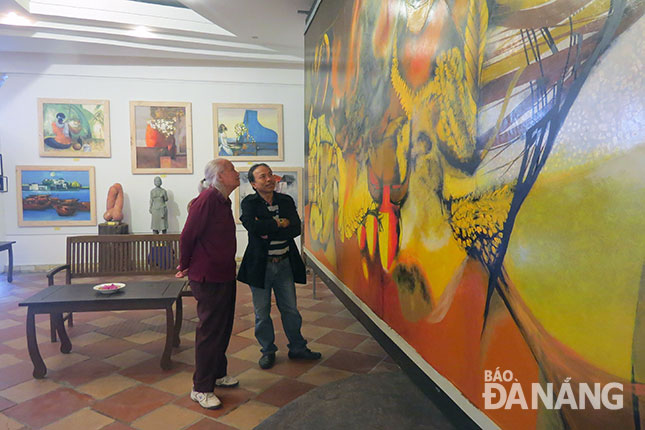 Một góc triển lãm “Mùa xuân” tại Studio Vũ Trọng Thuấn. TRONG ẢNH: Họa sĩ Vũ Trọng Thuấn (trái) giới thiệu bức tranh Việt Nam dài 12m của ông đang trưng bày tại triển lãm.