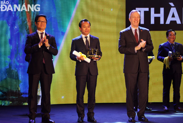 Secretary Anh (middle) receiving the souvenir cup in recognition of Da Nang’s top position in the PCI 2016 on behalf of the local leaders and citizens