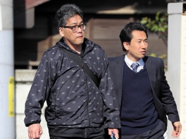 Shibuya Yasumasa (trái) được áp giải lên xe cảnh sát. (Nguồn: Asahi Shimbun)