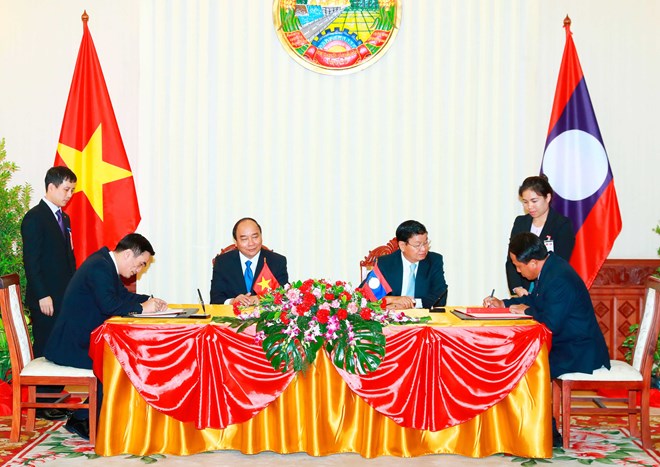 Prime Ministers Nguyen Xuan Phuc (L) and Thongloun Sisoulith witness the signing of cooperation documents (Photo: VNA)