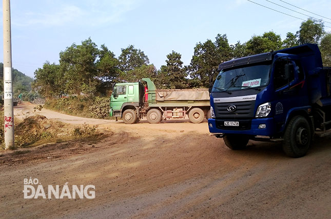 Xe tải chở đất đá phải đi vào đường công vụ mới (trái), nhưng vẫn còn 2 đơn vị cho xe chạy qua đường dân sinh vào thôn Phước Thuận (phải).           Ảnh: TRỌNG HUY