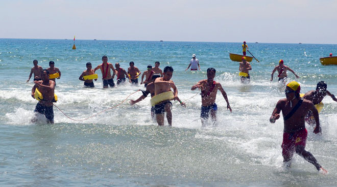 Nạn nhân chờ sẵn ngoài biển, các vận động viên chạy 100m rồi bơi đến (mang theo phao kẹp) để đưa nạn nhân vào vị trí an toàn. Ảnh: Thu Hà