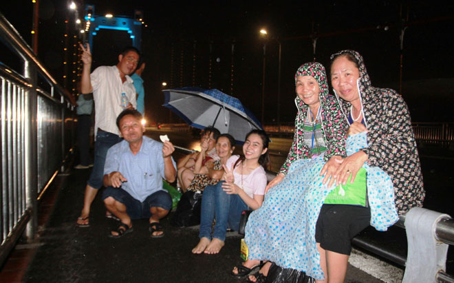 Bất chấp cơn mưa nhẹ hạt, nhiều du khách vẫn đi bộ lên quãng giữa cầu Thuận p