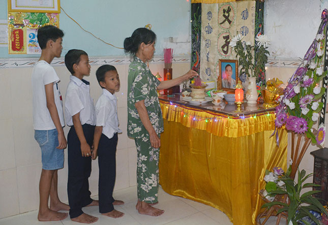 Mrs Chen and her grandchildren in front of her son’s altar