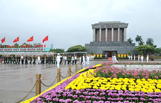 Various types of colourful flowers and Vietnamese people in front of the Ho Chi Minh Mausoleum.