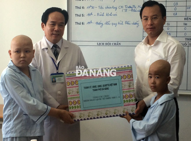   Secretary Anh (right) giving a gift to child patients at the city’s Cancer Hospital