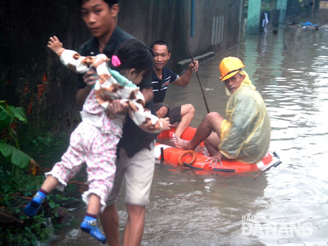 Người dân ở vùng thấp trũng thuộc khu vực đông nam nút giao thông Hòa Cầm đưa trẻ em lên vùng cao hơn vì bị ngập sâu trong nước mưa.