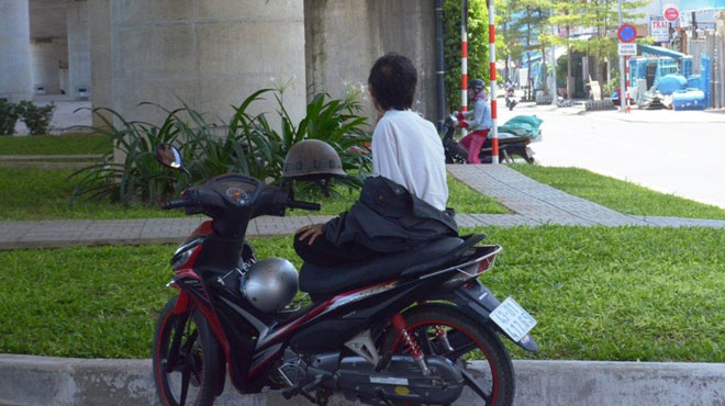 A ‘xe om’ (motorbike taxi) driver under a bridge 