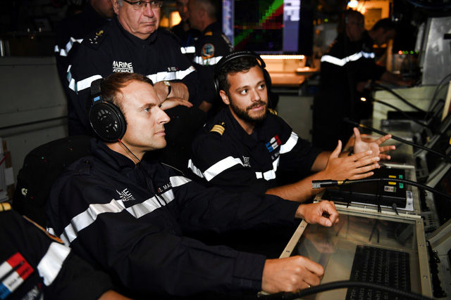 Tổng thống Macron (trái) Tham mưu trưởng Hải quân Pháp, Đô đốc Bernard Rogel (đứng), nghe một chuyên gia về sóng âm trên tàu ngầm Le Terrible giải thích về cách tàu ngầm theo dõi các hoạt động xung quanh. (Ảnh: Reuters)